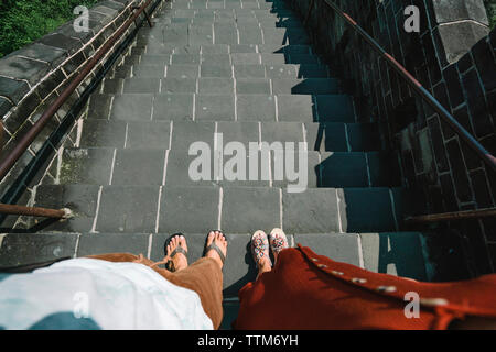 Low section of friends standing on steps during sunny day Stock Photo