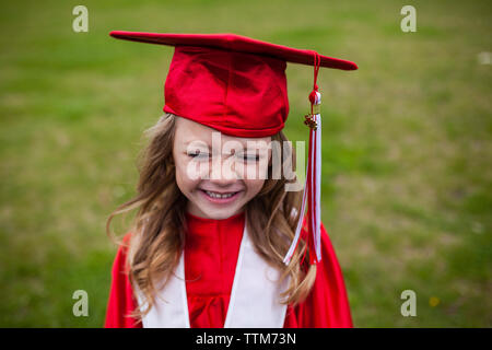 Happy girl in graduation gown on field Stock Photo
