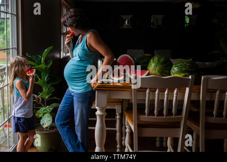 Mother and daughter eating watermelon at home Stock Photo