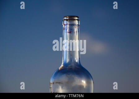 Isolated neck of empty red wine bottle against blue evening sky Stock Photo