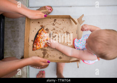Overhead view of mother giving pizza to daughter Stock Photo