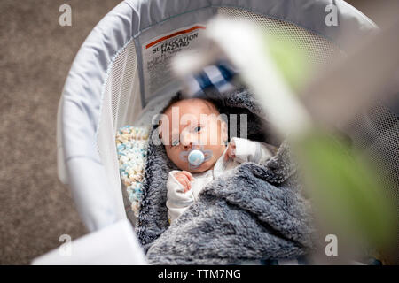 High angle portrait of baby boy with pacifier lying in crib at home Stock Photo