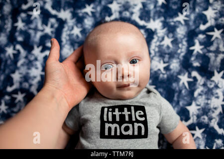 Cropped hand of mother holding son's head on mattress Stock Photo