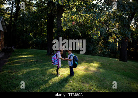 Brother and sister siblings waiting for school bus sunny morning Stock Photo