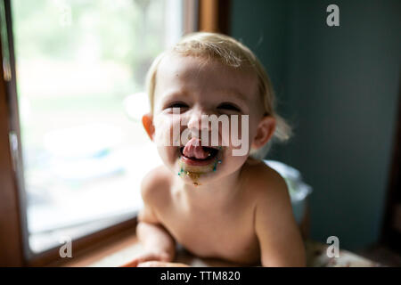 Toddler girl licking sprinkles off lips after eating sweet treat Stock Photo