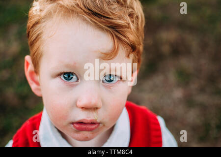 Close-up portrait of sad baby boy standing on field Stock Photo