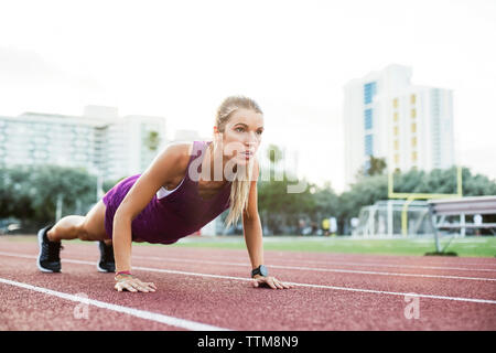 Determined female athlete doing push-ups on race tracks Stock Photo