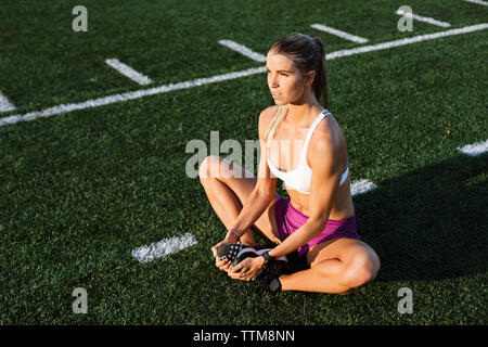 High angle view of female athlete performing short adductor stretch on field Stock Photo