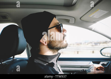 Side view of man wearing knit hat while driving car Stock Photo