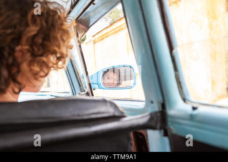 Western girl's face reflected in the wing mirror of vintage car, Cuba Stock Photo