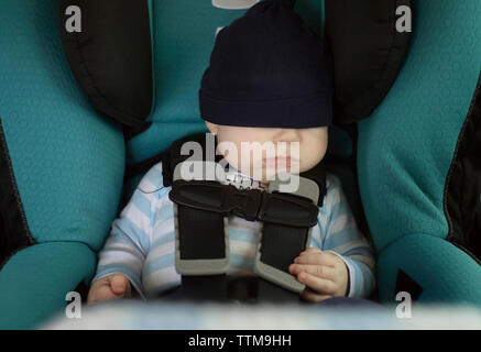 Baby boy sleeping while sitting in car Stock Photo