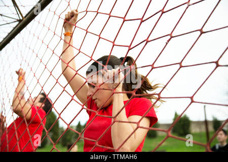 Low angle view of woman climbing netting during race Stock Photo