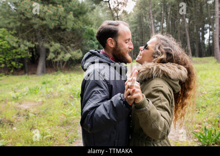 Side view of happy loving couple looking at each other in forest Stock Photo