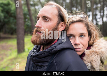 Thoughtful loving couple looking away in forest Stock Photo