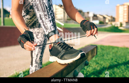 Low section of woman tying shoelaces at park Stock Photo