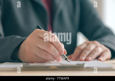 Businesswoman signing contract and business partnership agreement at office desk, close up of hands writing signature Stock Photo