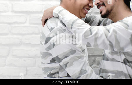 Midsection of smiling gay couple romancing by wall at home Stock Photo