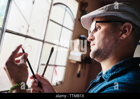 Man working as painter checking brush and pencil tip before painting Stock Photo