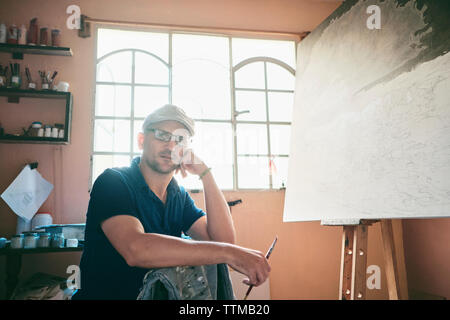 Portrait of man working as painter holding brush in workshop Stock Photo
