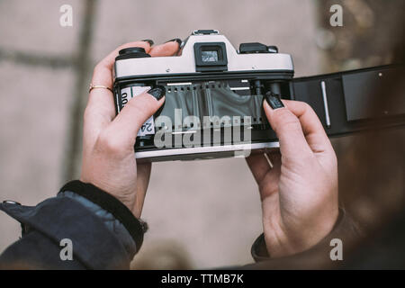 Close-up of woman loading film negative in vintage camera on footpath Stock Photo