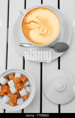 Cappuccino and refined sugar in white bowl on wooden table Stock Photo
