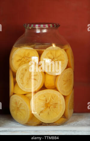 Preserved lemon slices in glass jar on white wooden shelf Stock Photo