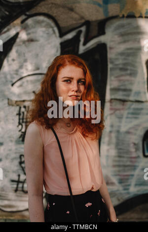 Portrait of young confident  woman standing against wall in city Stock Photo