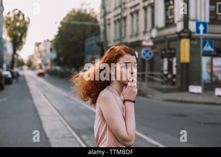Young woman smoking while crossing road in city Stock Photo