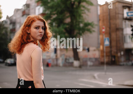 Young redheaded woman walking in city street Stock Photo