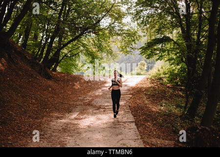 Front view of young woman running at park on sunny day Stock Photo