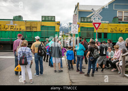 USA Alaska, Sitka, individuals walking the streets of downtown Sitka wait for the train traveling on the White Pass & Yukon Route Railroad to pass Stock Photo