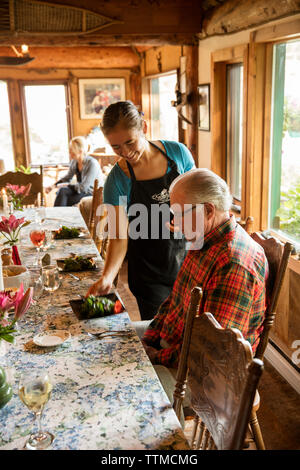 USA, Alaska, Homer, China Poot Bay, Kachemak Bay, dinner being served at the Kachemak Bay Wilderness Lodge Stock Photo