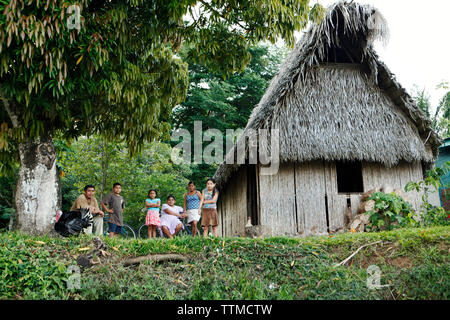 BELIZE, Punta Gorda, Toledo, a family sits in front of their home on the side of the road near the Li Punit Ruins Stock Photo