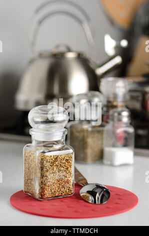 Dried oregano in the glass bottle on the kitchen table Stock Photo