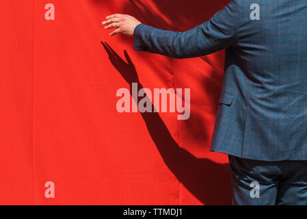 Grand opening, businessman opens red curtain to reveal product. Unrecognizable person with copy space. Stock Photo
