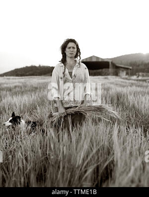 USA, California, woman standing with crops in field (B&W) Stock Photo