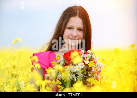 Sweet girl in meadow with wild spring flowers Stock Photo