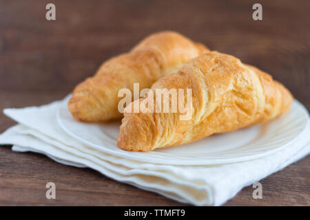 fresh delicious croissants on a plate on a wooden background Stock Photo