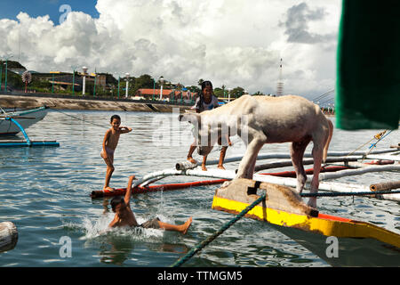 PHILIPPINES, Palawan, Puerto Princesa, kids play on fishing boats in the City Port Area Stock Photo