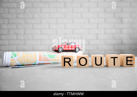 Cubes with word ROUTE, map and toy car on brick wall background Stock Photo