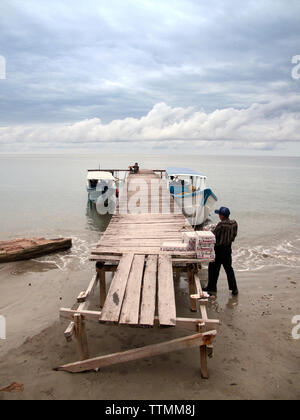 INDONESIA, Mentawai Islands, man carrying supplies to load onto boats at boat dock Stock Photo