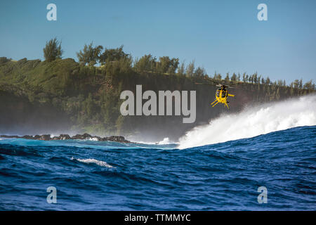 USA, HAWAII, Maui, Jaws, a helicopter hovering over the big waves and surfers at Peahi on the Northshore Stock Photo