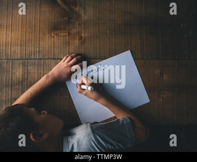 Overhead view of boy writing letter to Santa Claus on wooden table during christmas Stock Photo