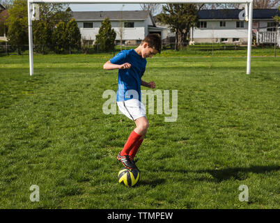 Full length of boy playing with soccer ball on field Stock Photo