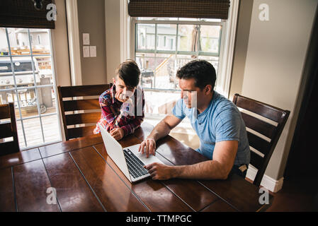 Father using laptop computer by son at home Stock Photo