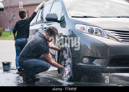 Father and son washing car together on driveway Stock Photo