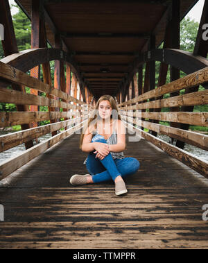 Portrait of confident woman sitting on wooden covered bridge Stock Photo