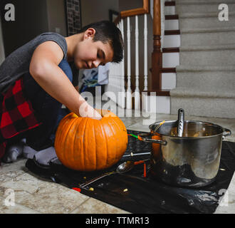 Serious boy removing seeds from pumpkin for Jack O' Lantern at home Stock Photo