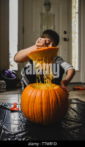 Boy removing seeds from fresh pumpkin at home Stock Photo