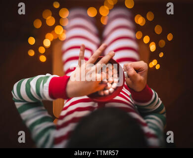 Overhead shot of child taking marshmallow out of cup of hot cocoa. Stock Photo